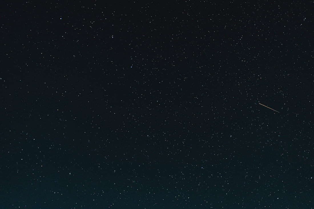 a night sky with stars and a plane in the distance