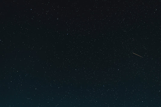 a night sky with stars and a plane in the distance