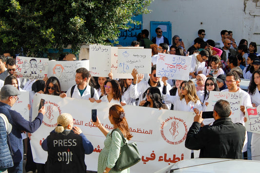 Protesters hold signs and banners at a rally.
